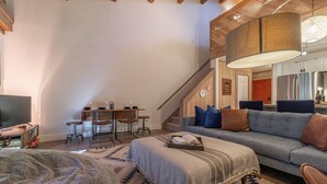 Una sala de estar acogedora con sofá, reposapiés y un comedor con sillas y una mesa.
