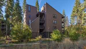 Un edificio de varios pisos con una escalera que conduce a un nivel superior, rodeado de árboles y vegetación.