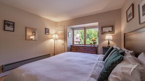 A bedroom with a large bed, a dresser, and a window with a view of greenery. - Palisades Tahoe Condo~Walk to the Village~(#30) (Olympic Valley)