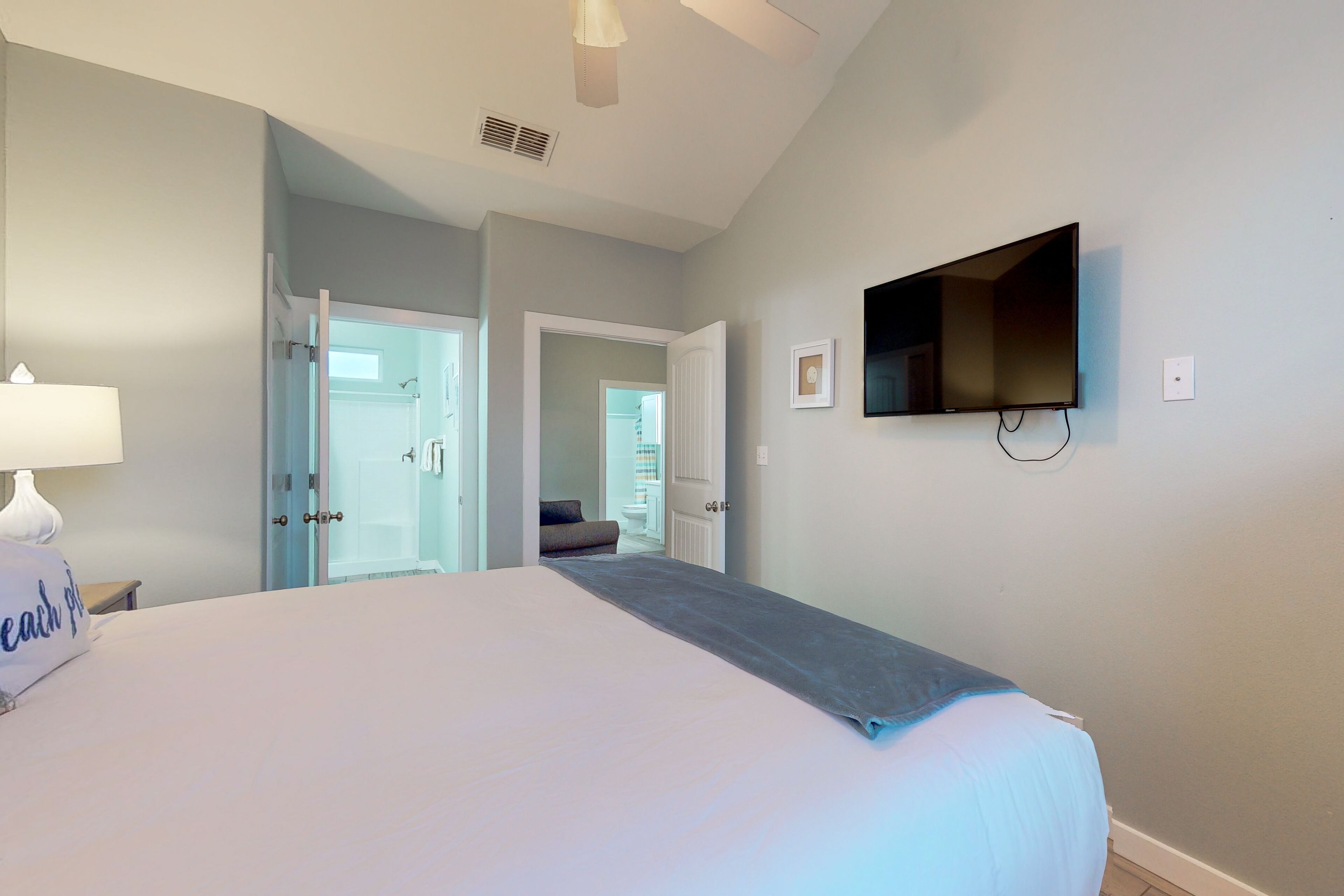 A hotel room with a bed, a TV mounted on the wall, and a door leading to a bathroom.