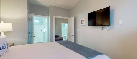 A hotel room with a bed, a TV mounted on the wall, and a door leading to a bathroom.