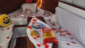 L’intérieur d’un chalet accueillant, avec un lit, une petite table, un ours en peluche, un coussin orné d’un visage souriant et quelques collations.