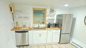 A compact kitchen with white cabinetry, a stainless steel dishwasher, a microwave, and a refrigerator. - 2-Bedroom in the Heart of Denver (Denver)