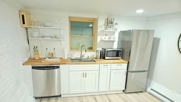 A compact kitchen with white cabinetry, a stainless steel dishwasher, a microwave, and a refrigerator. - 2-Bedroom in the Heart of Denver (Denver)
