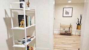 A hallway with a white bookshelf, wooden flooring, and a small table with a plant. - 2-Bedroom in the Heart of Denver (Denver)