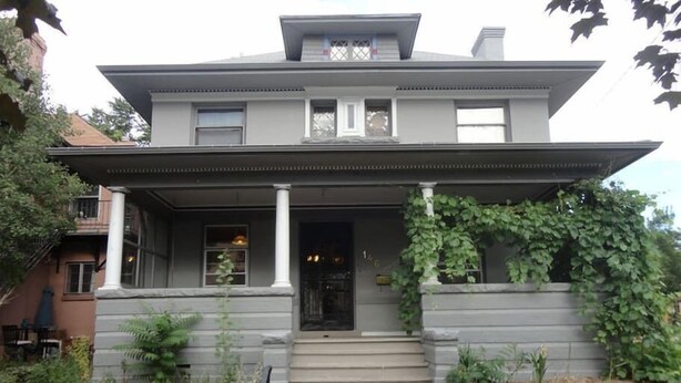 A two-story house with a front porch, a covered entryway, and a small front yard. - 2-Bedroom in the Heart of Denver (Denver)
