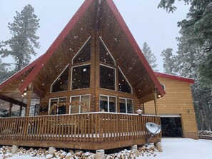 A wooden cabin with a red roof and large windows, surrounded by snow-covered ground and trees. - Fun for the kids and GREAT Kitchen (Duck Creek Village)