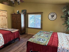 Un dormitorio con dos camas, muebles de madera, una ventana con persianas y un reloj de pared antiguo.