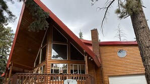 Una cabaña de troncos con una terraza grande, un garaje y una chimenea.