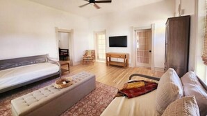 Una sala de estar amplia con sofá, reposapiés y televisor en la pared.