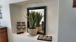 A white wall with a mirror reflecting a potted plant and decorative items. - Spacious 4-bedroom suburban retreat in San Diego! Backyard, BBQ, Pool & Jacuzzi  (San Diego)