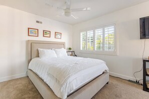A bedroom with a large bed, a ceiling fan, a window with blinds, and three framed pictures on the wall. - Spacious 4-bedroom suburban retreat in San Diego! Backyard, BBQ, Pool & Jacuzzi  (San Diego)
