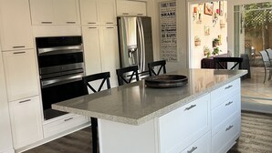 A modern kitchen with white cabinetry, a stainless steel refrigerator, an oven, and a granite countertop island. - Spacious 4-bedroom suburban retreat in San Diego! Backyard, BBQ, Pool & Jacuzzi  (San Diego)
