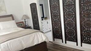 A bedroom with a wooden floor, a bed with a white bedspread, a nightstand with a lamp, and a dresser with a mirror. - Spacious 4-bedroom suburban retreat in San Diego! Backyard, BBQ, Pool & Jacuzzi  (San Diego)