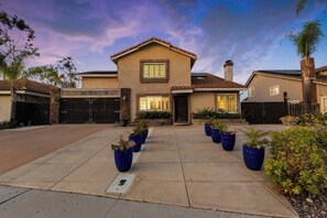A two-story house with a tiled roof, a front garage, and a driveway leading to the entrance. - Spacious 4-bedroom suburban retreat in San Diego! Backyard, BBQ, Pool & Jacuzzi  (San Diego)