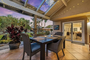 An outdoor patio with a table and chairs, surrounded by potted plants and a view of the sky. - Spacious 4-bedroom suburban retreat in San Diego! Backyard, BBQ, Pool & Jacuzzi  (San Diego)