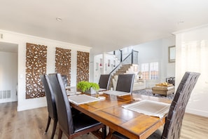 A dining area with a wooden table, black chairs, and decorative panels. - Spacious 4-bedroom suburban retreat in San Diego! Backyard, BBQ, Pool & Jacuzzi  (San Diego)