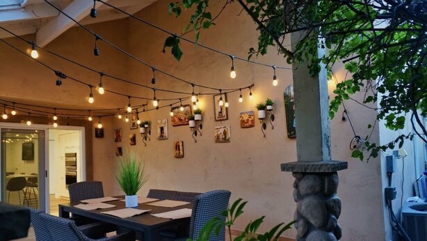 An outdoor patio area with string lights, wicker furniture, and potted plants. - Spacious 4-bedroom suburban retreat in San Diego! Backyard, BBQ, Pool & Jacuzzi  (San Diego)
