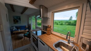 A compact kitchen with a window, a sink, and a stove. - Lovely cottage with wilderness bath and view (Holbæk)