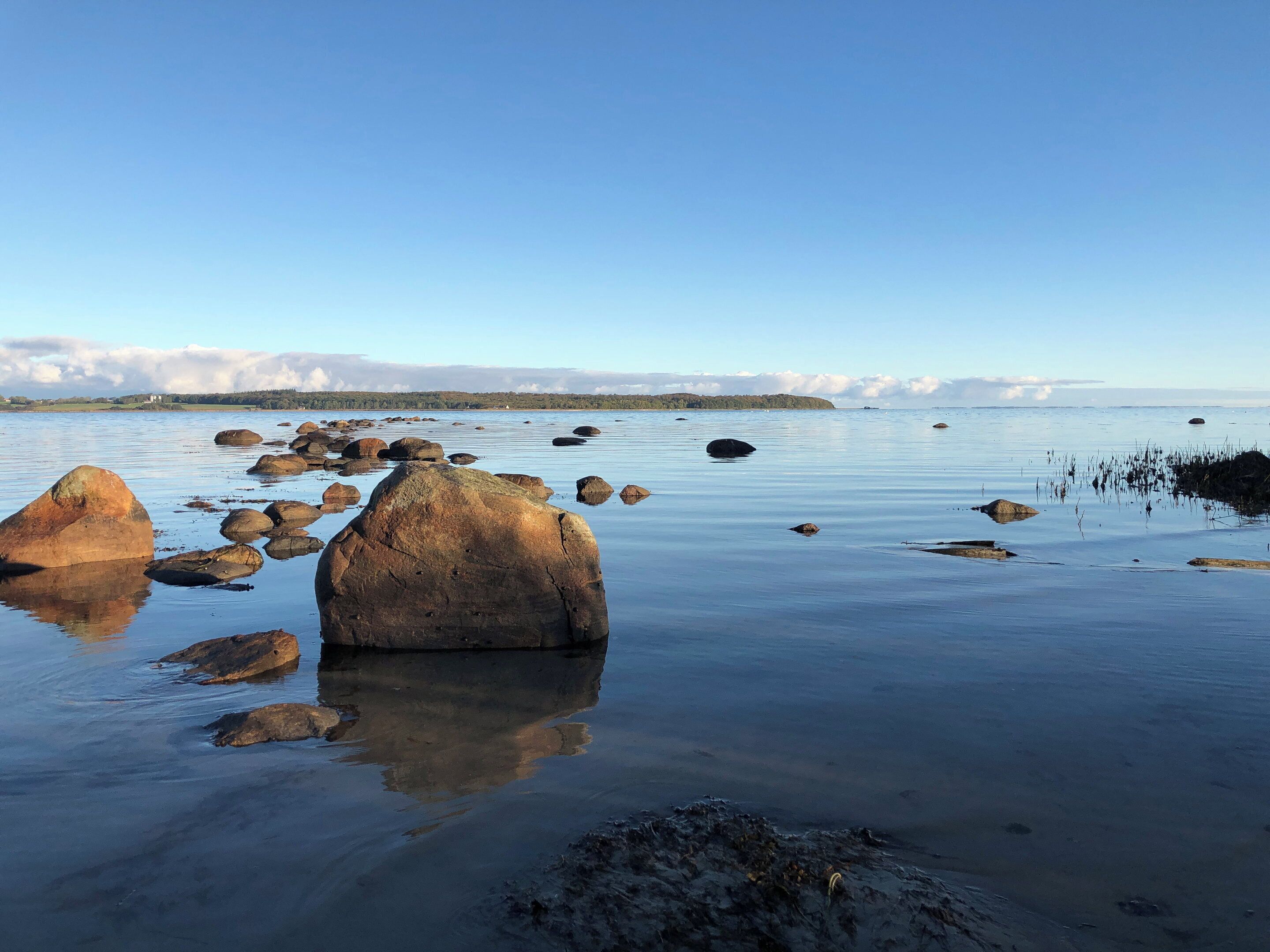 A calm lake with large rocks and clear skies.