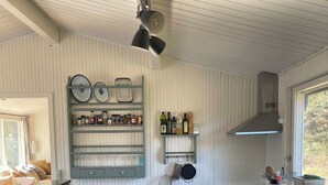Une cuisine avec des panneaux muraux blancs, un four encastré, un évier et un ventilateur de plafond.