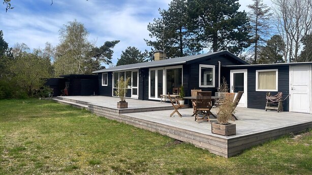 Une maison moderne dotée d’une terrasse, de portes-fenêtres coulissantes et d’un petit espace patio.