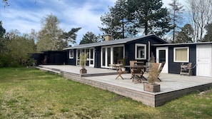 A modern house with a deck, sliding glass doors, and a small patio area. - Summer house with outdoor sauna at Sjællands Odde (Sjællands Odde)