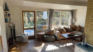 Un salon confortable avec un canapé, une petite table et une fenêtre donnant sur un jardin.