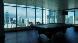 A room with a pool table, large windows, and a city view. - Beautiful Apt, Best Location 2BR, Best Location (Panamá)