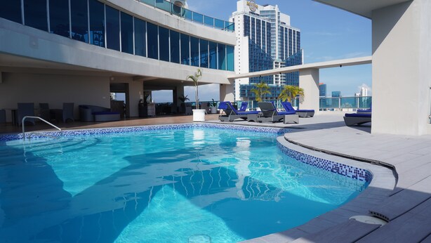 A rooftop pool with clear blue water, lounge chairs, and a modern building in the background. - Beautiful Apt, Best Location 2BR, Best Location (Panamá)