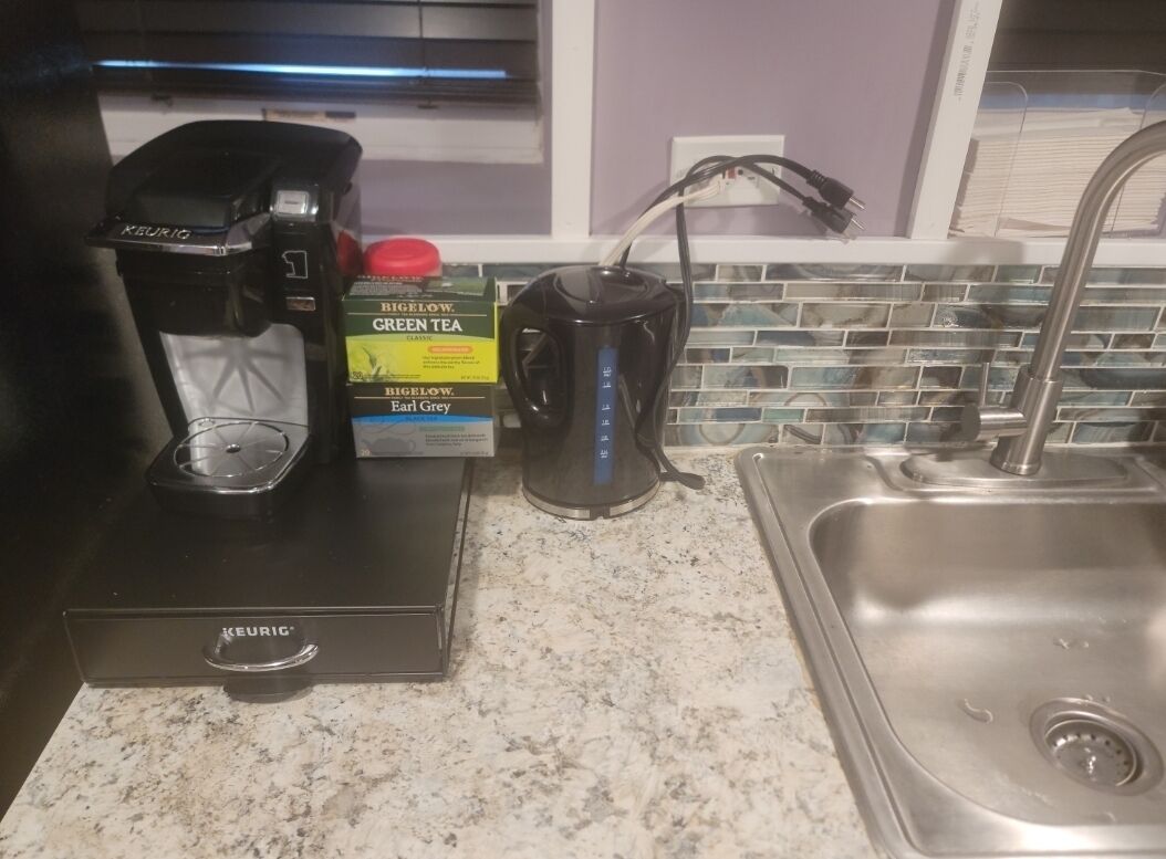 A kitchen with a Keurig coffee maker, a kettle, and boxes of Bigelow Earl Grey tea.