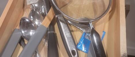 A drawer containing various kitchen utensils including spoons, a strainer, and a spatula.
