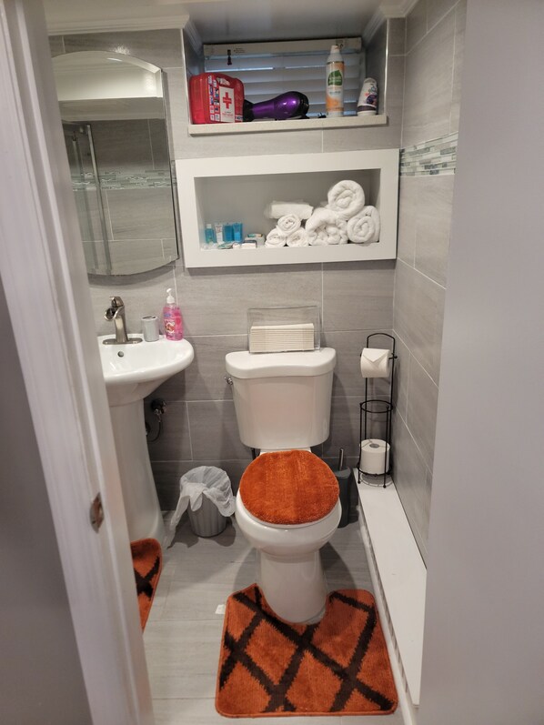 Une salle de bain équipée de toilettes, d’un lavabo et d’étagères au-dessus des toilettes.
