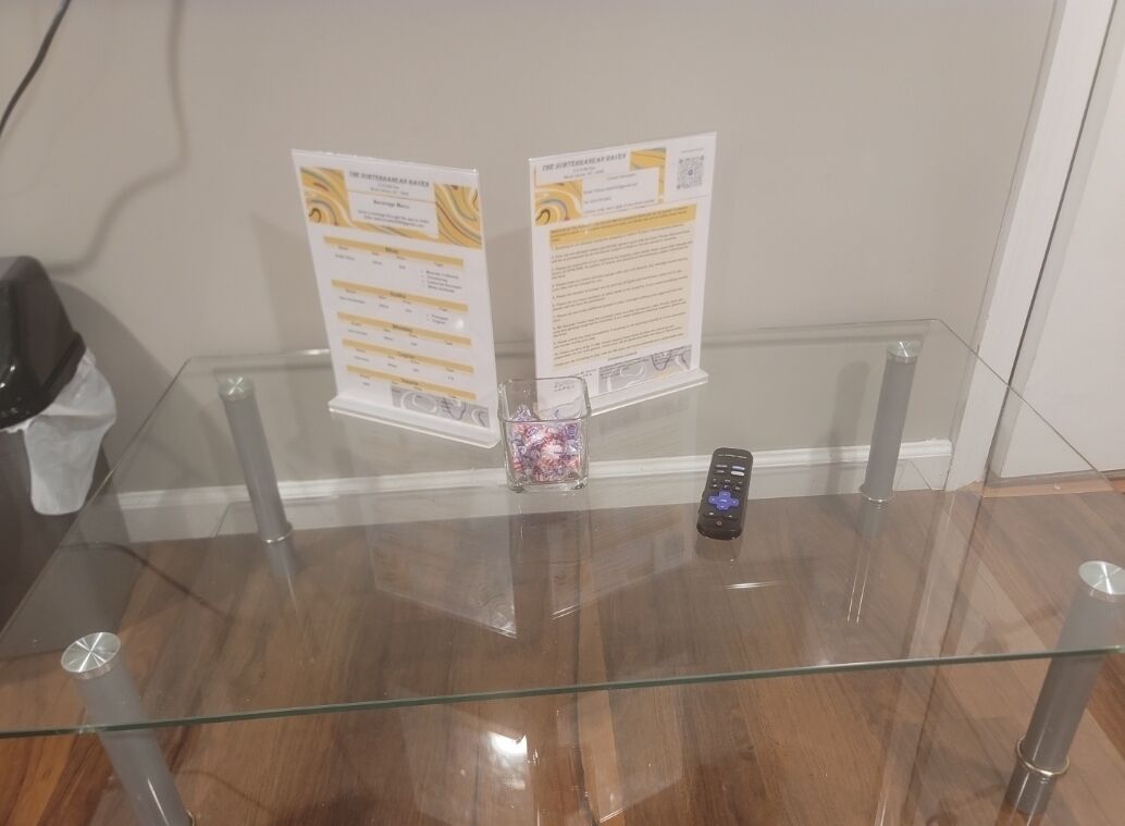 A glass-top table with two informational brochures, a glass container, and a remote control.