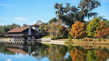 Un hôtel situé au bord d’un lac, doté d’une façade en pierre, d’un patio couvert et entouré d’un feuillage automnal.