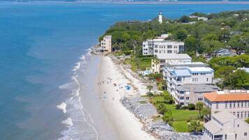 Un hôtel situé sur la côte, avec accès direct à la plage, composé de plusieurs bâtiments et avec un phare en arrière-plan.