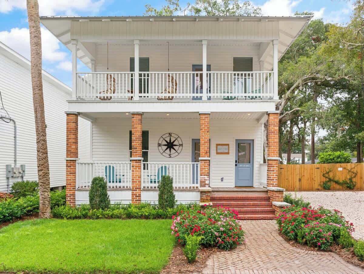 Une maison à deux étages avec un balcon, un motif décoratif en forme de boussole et une colonne en briques.