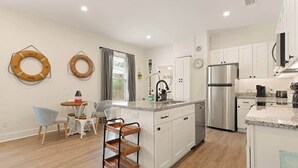 Una cocina moderna con armarios blancos, un refrigerador de acero inoxidable y una encimera de granito.
