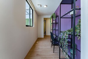 Stylish hallway with a black shelving unit, greenery, and a window offering a view of lush surroundings.