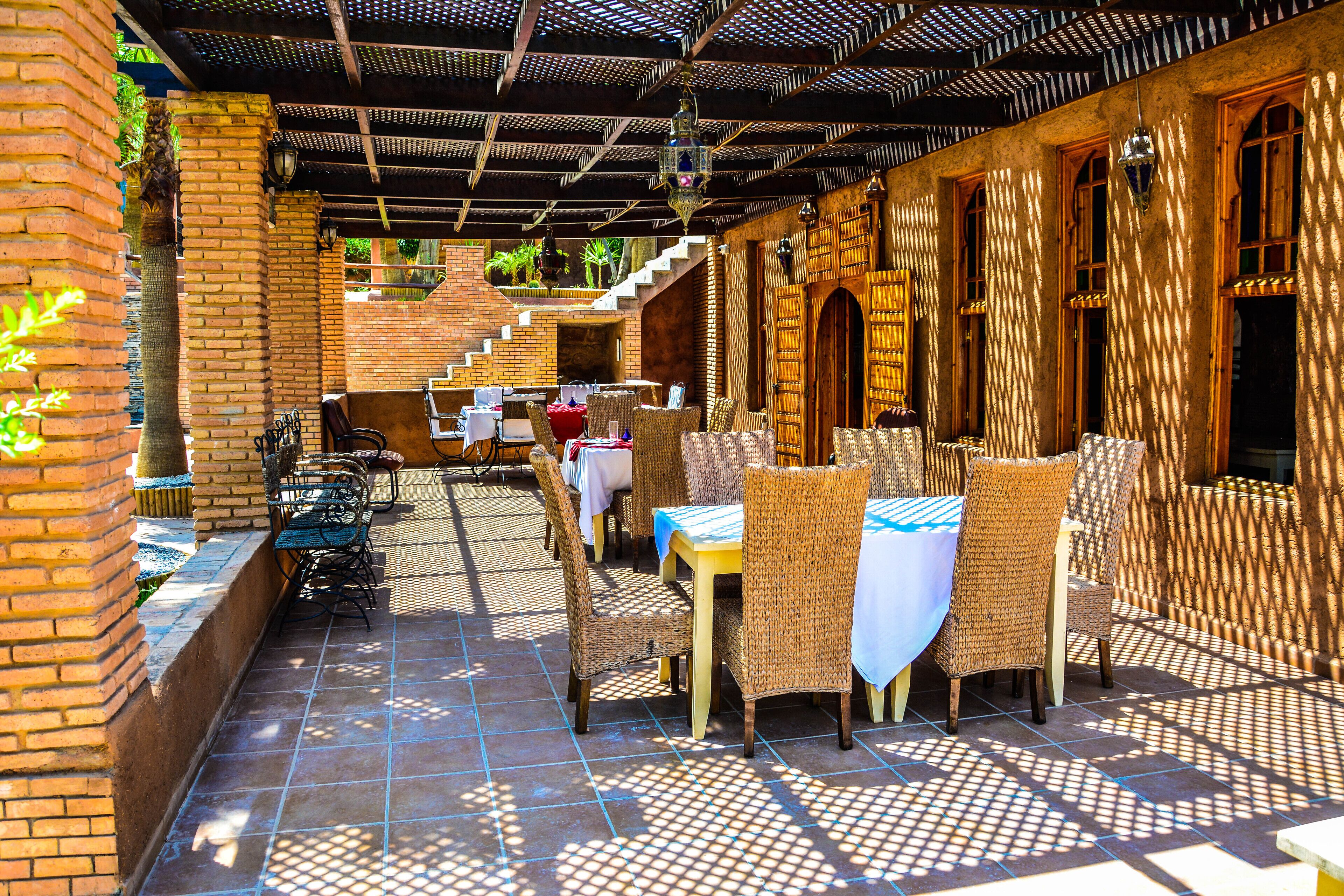 Un patio al aire libre con mobiliario de mimbre y paredes de ladrillo.
