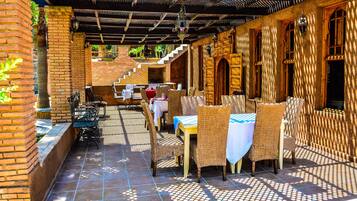 Un patio al aire libre con mobiliario de mimbre y paredes de ladrillo.