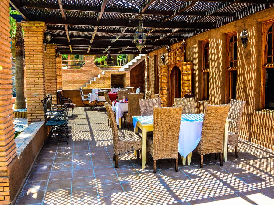Un patio al aire libre con mobiliario de mimbre y paredes de ladrillo.