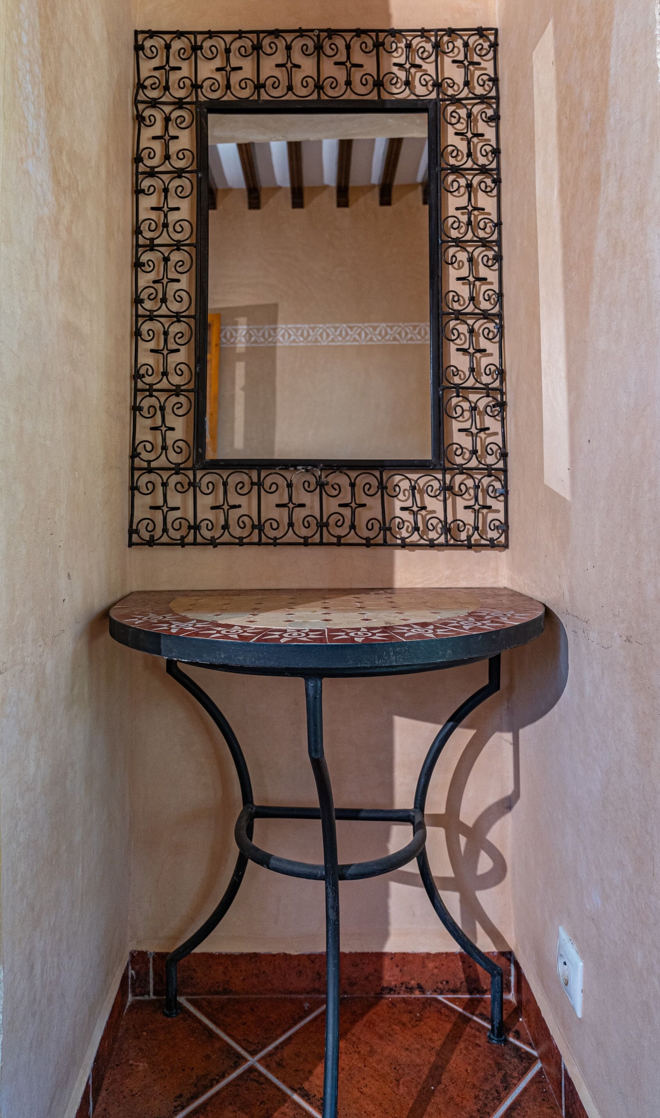 Un racó amb una taula rodona petita, una estructura metàl·lica decorativa i un paviment de rajoles.