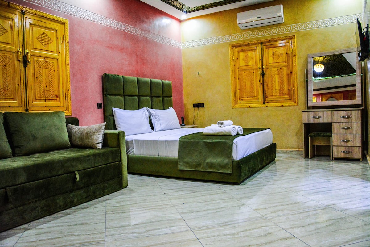 Una habitación de hotel con cama, sofá, cómoda y espejo.