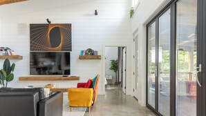 A spacious living area with a modern fireplace, a large flat-screen TV, and a bright yellow armchair.