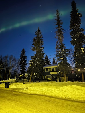 A house surrounded by snow-covered ground and tall evergreen trees.