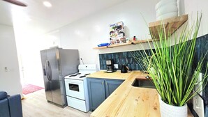 A modern kitchen with a stainless steel refrigerator, a white stove, and a wooden countertop.