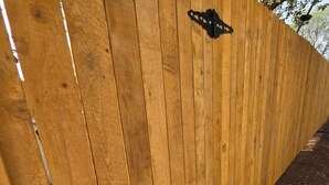 A wooden fence with a metal gate and a small black object on it.