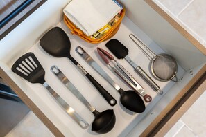 Eine Schublade mit Küchenutensilien, darunter ein Pfannenwender, eine Kelle und ein Sieb.
