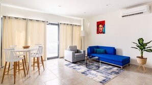 Una sala de estar moderna con un sofá azul, una mesa de comedor blanca y sillas.